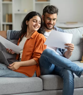 happy couple on couch reviewing finances