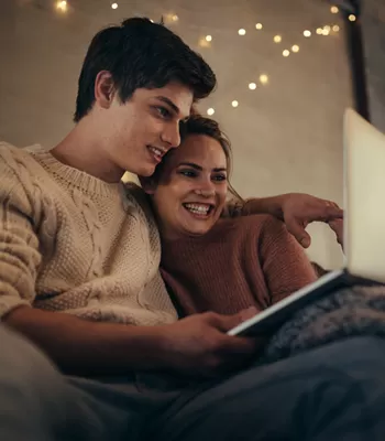 couple using computer sitting on couch