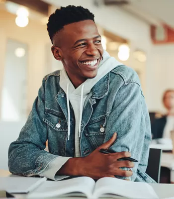 young man sitting in classroom smiling